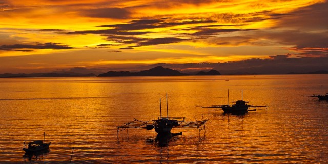 Boats on water at sunset